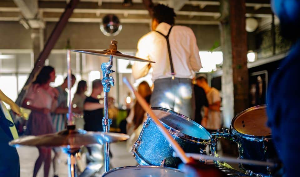 live-music | Hideaways Beach Resort Exuma, GeorgeTown Vacation Rentals Drummer playing a blue drum kit at a lively indoor party; blurred dancers in the background.